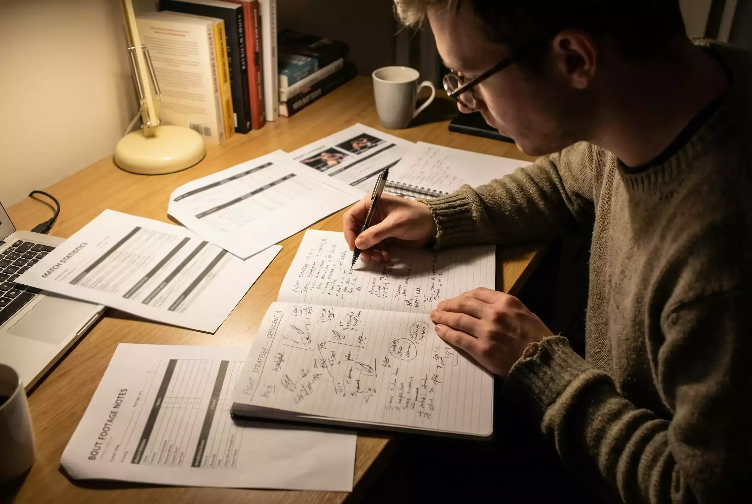 Person macht handschriftliche Notizen zur Kampfanalyse in einem Notizbuch